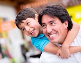 Father and son smiling with son on the father's back 